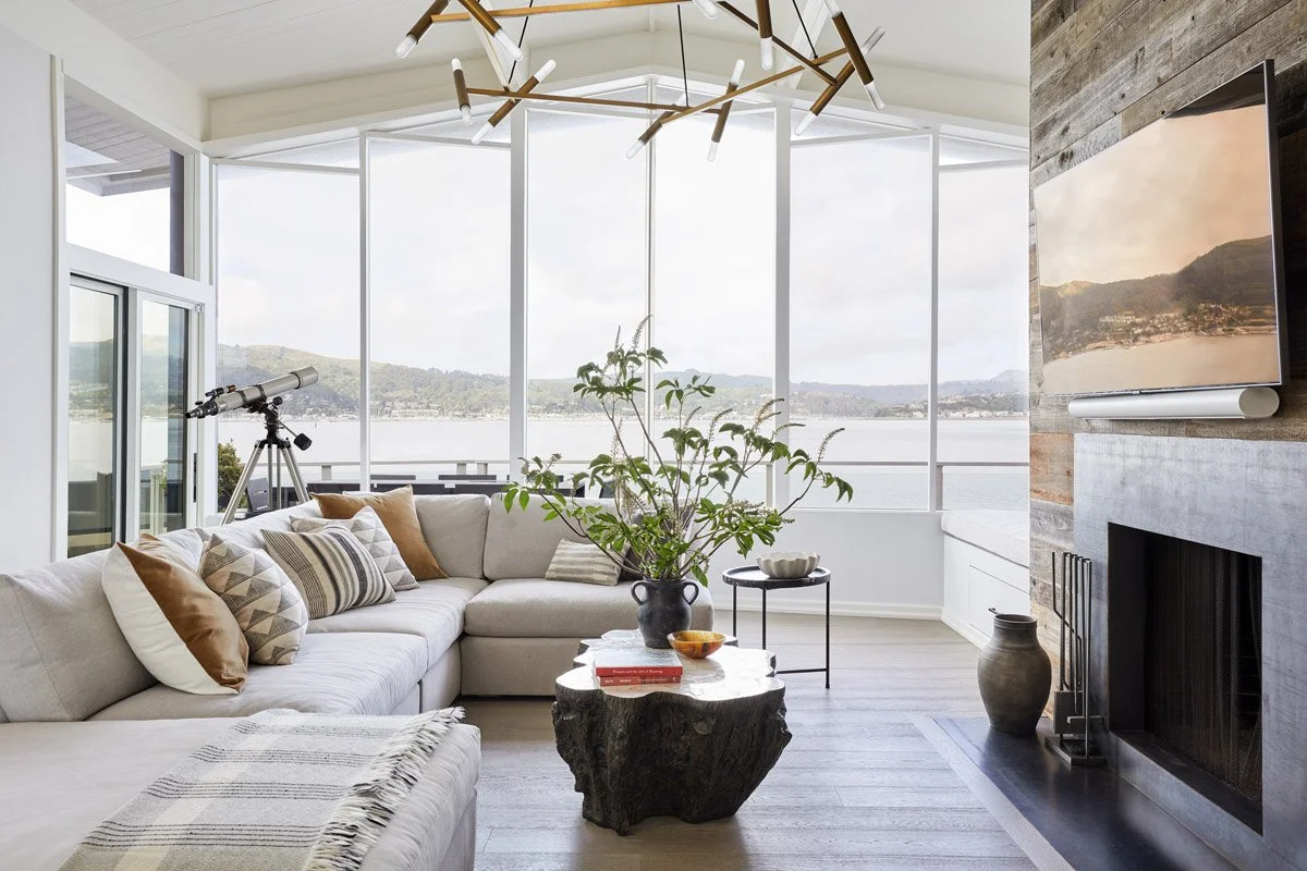 waterfront living room with sectional sofa, wood coffee table and sculptural chandelier