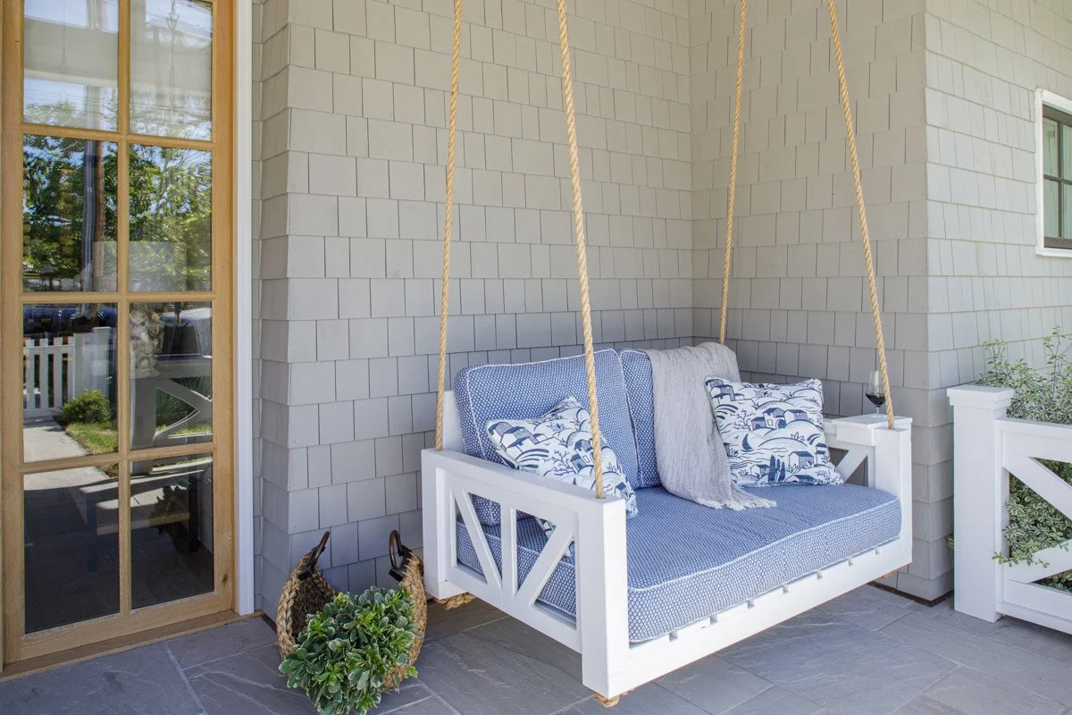 porch swing bed with blue cushions beside a glass-paned door