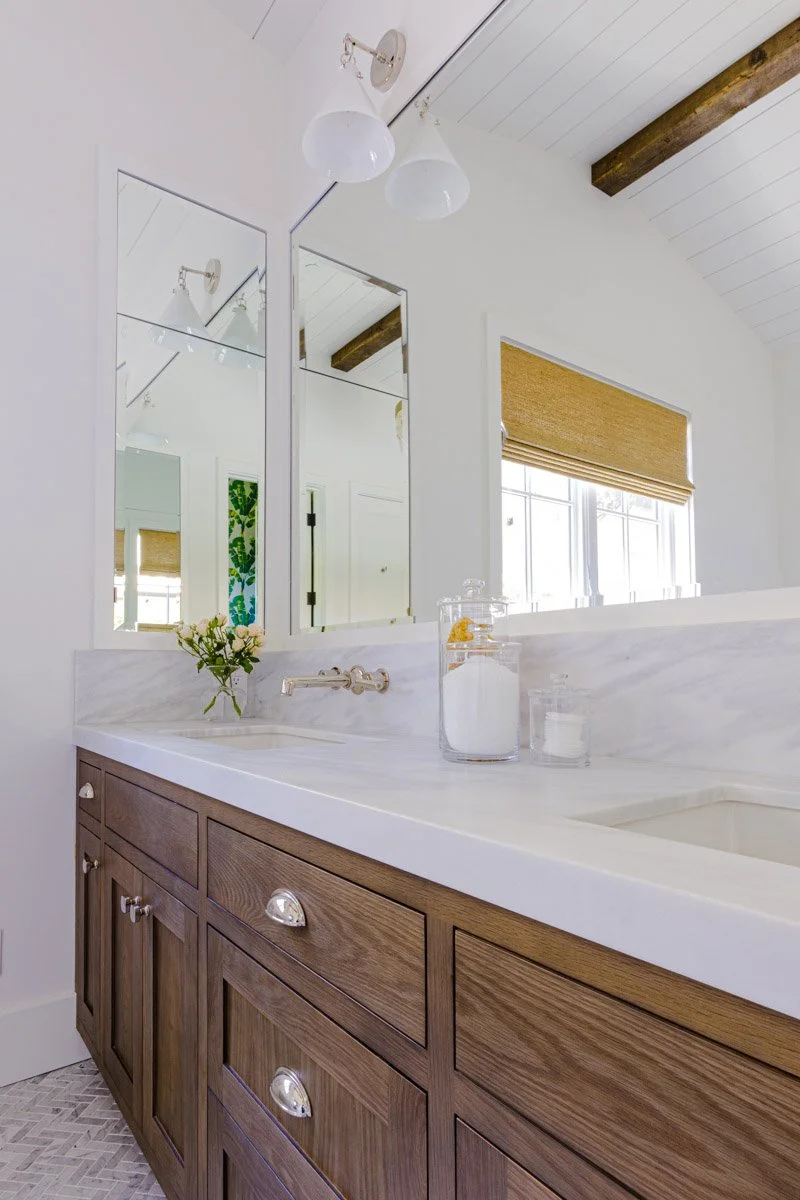 primary bathroom with dark wood vanity, marble countertop and woven shades