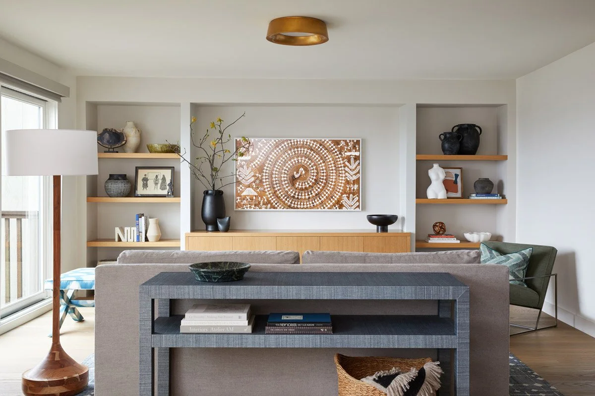 living room with built-in shelving, grey console table and carved wood art