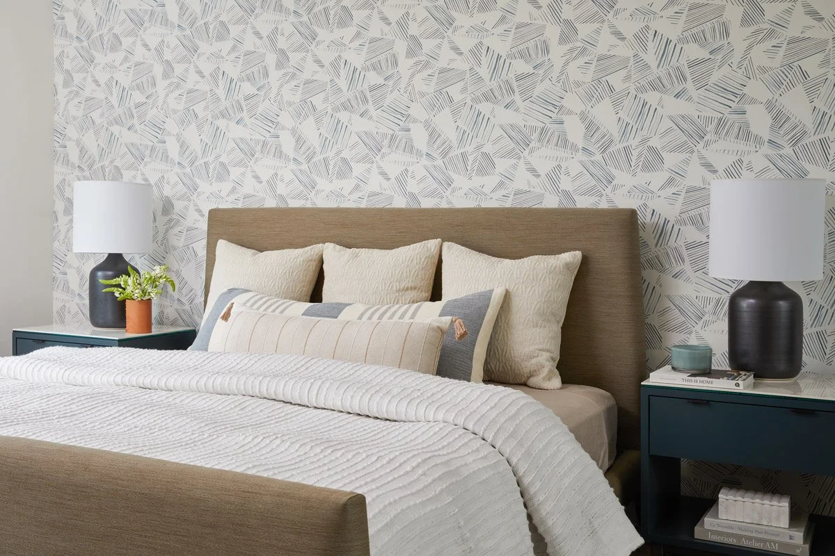 guest bedroom with leaf wallpaper, matching lamps and textured white bedding
