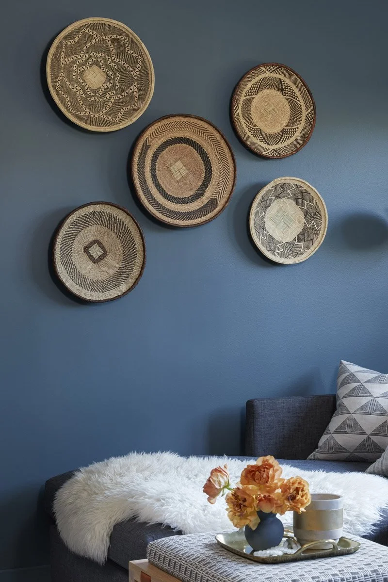 woven wall baskets above a sectional sofa with sheepskin throw