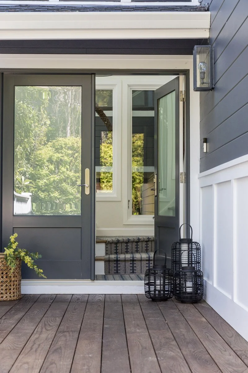 entry with charcoal glass door, wide plank wood floor and white wainscoting