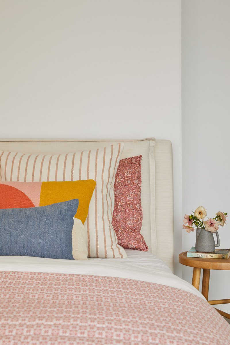 upholstered bed with colourful pillows and a small side table