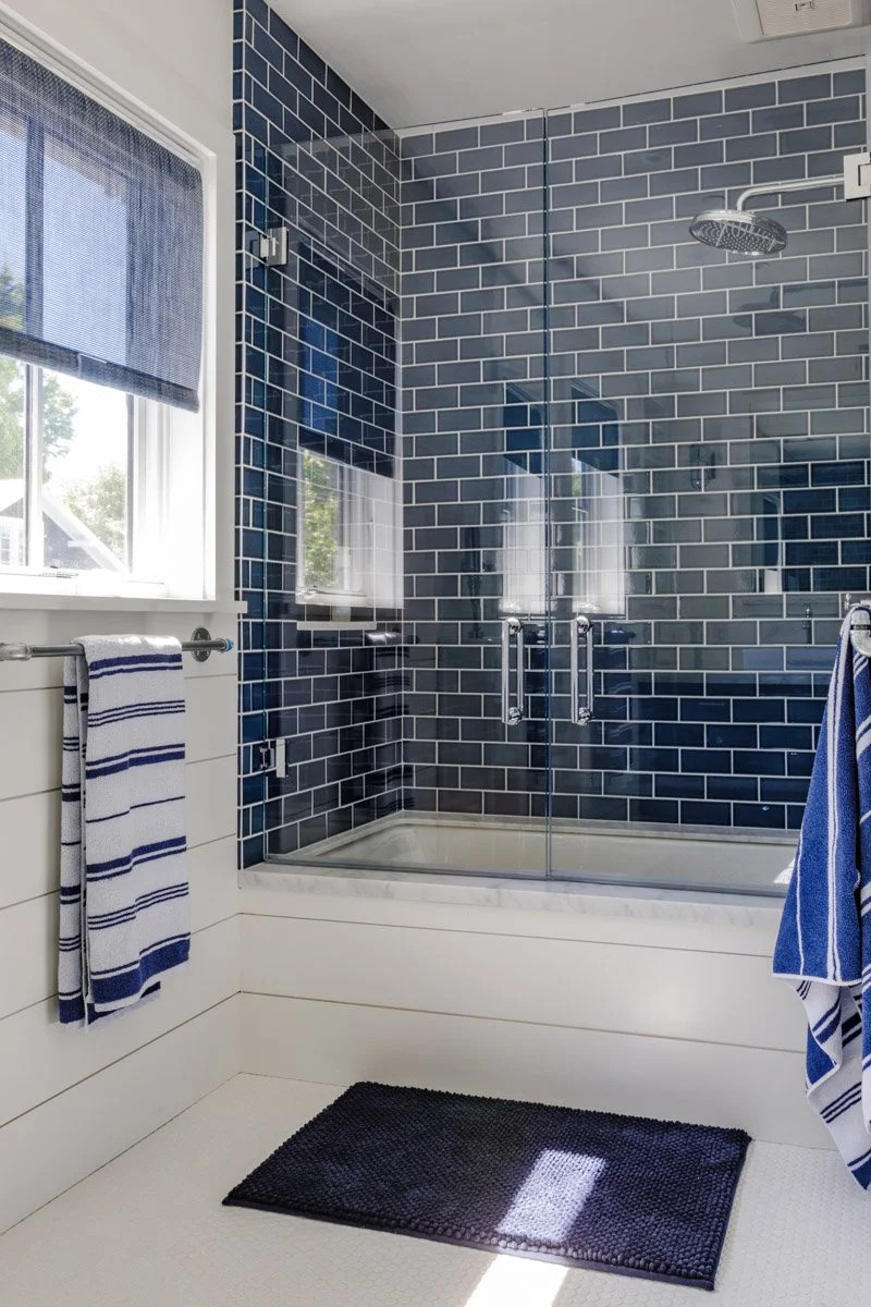 bathroom with navy subway tile shower and striped towels