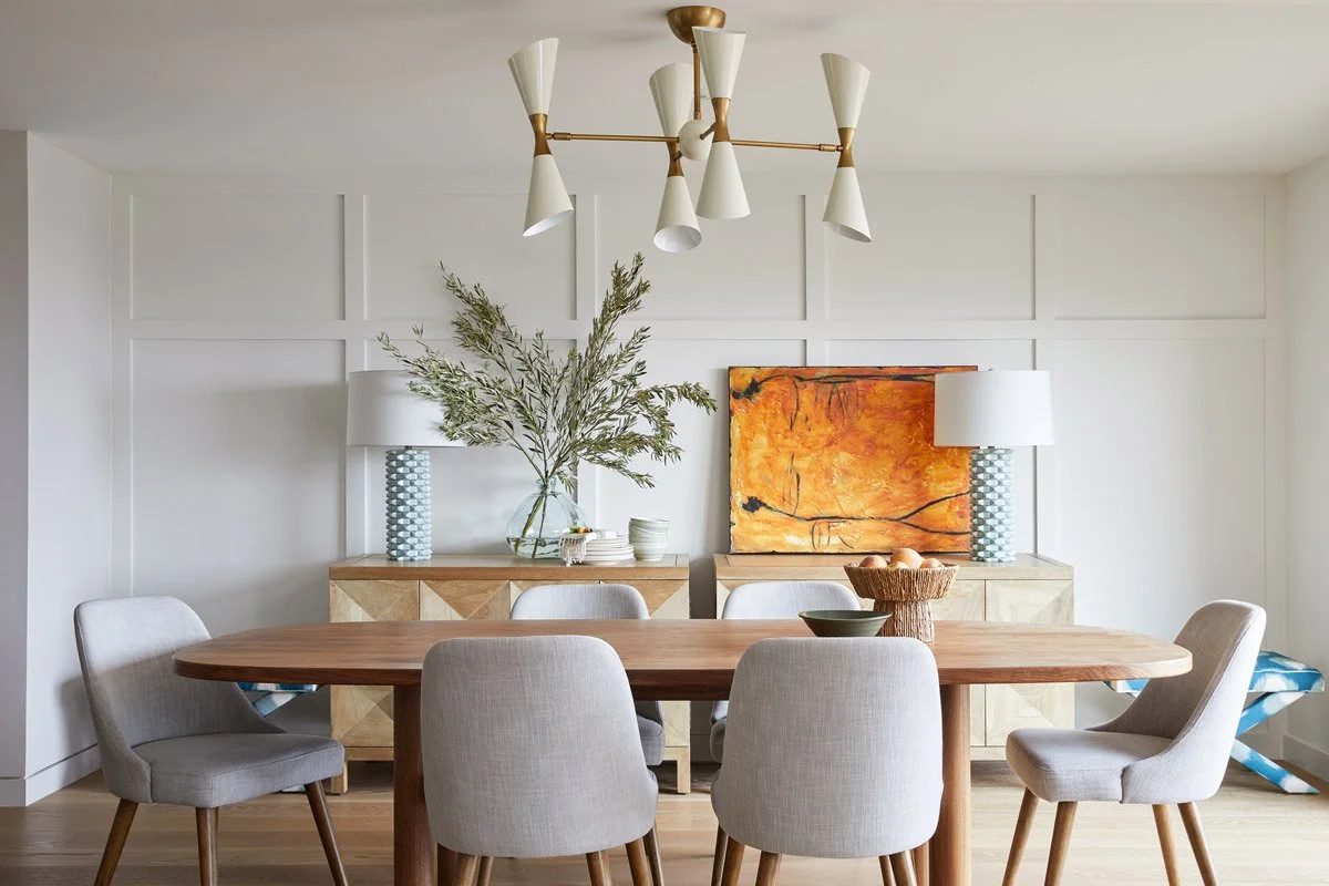 dining room with panelled walls, abstract art and brass chandelier