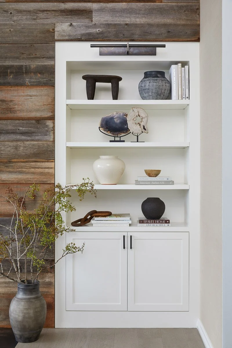 white built-in shelving beside a reclaimed wood wall