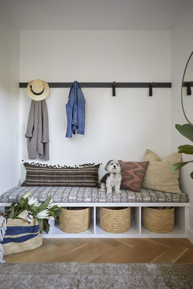 mudroom bench with patterned cushions, woven baskets and wall-mounted hooks