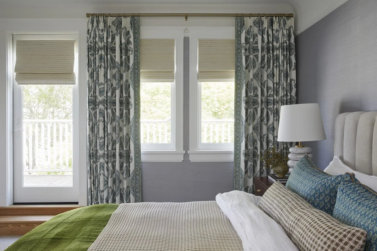 primary bedroom with botanical curtains, woven roman shades and French doors