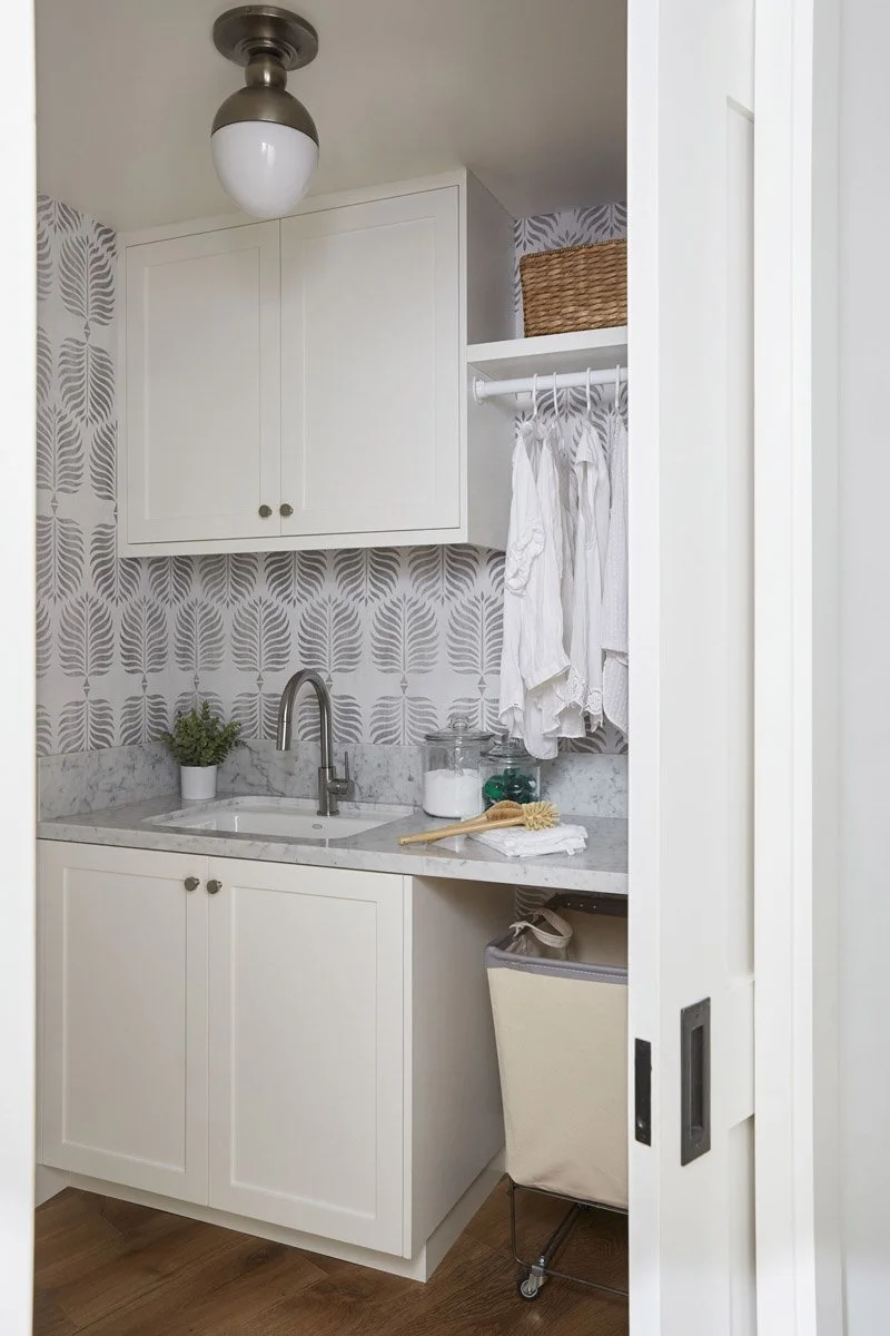 laundry room with patterned tile, white cabinetry and hanging rail