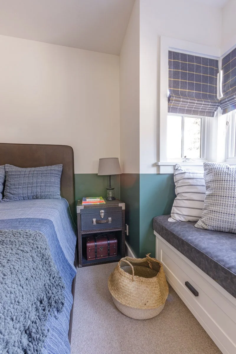 kids bedroom with window seat, green panelled wall and navy bedding