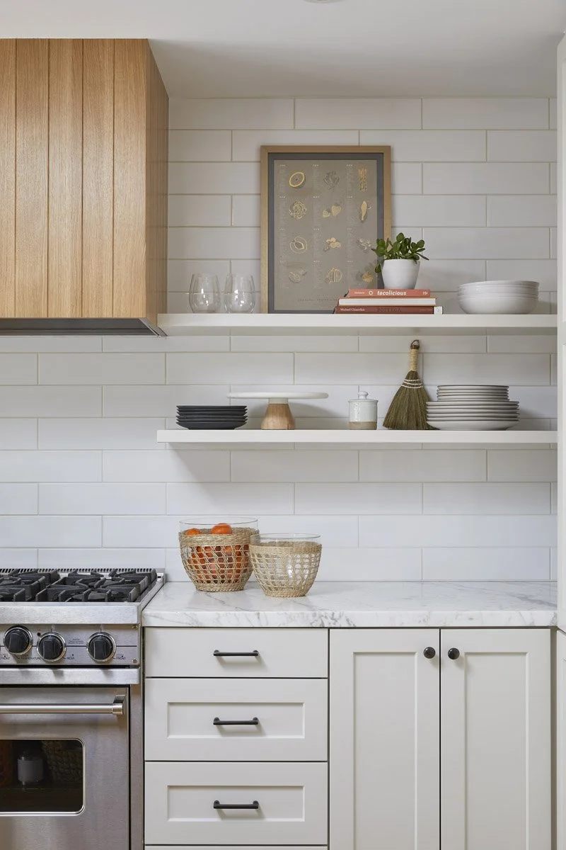 open shelving above a range with white subway tile and white oak cabinet