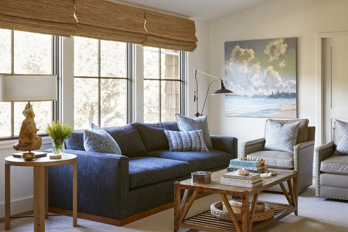 family room with navy sofa, wooden coffee table and woven roman shades