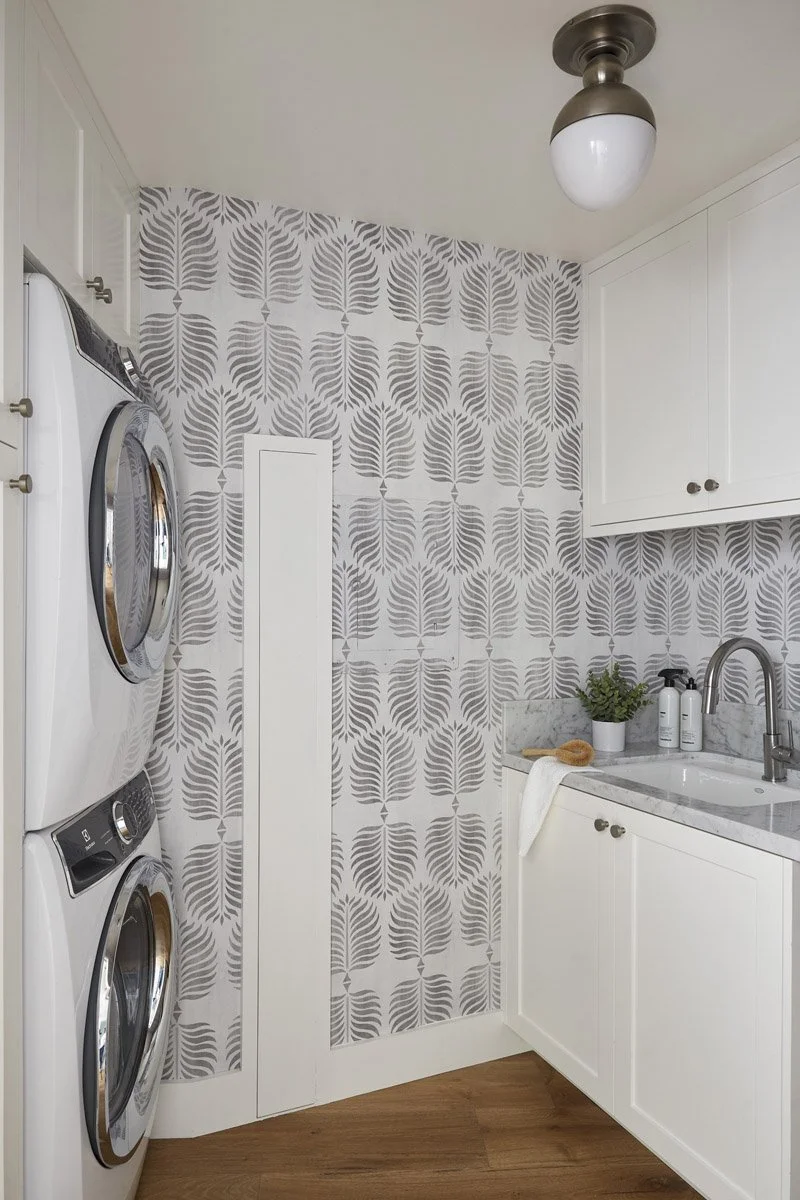 laundry room with stacked washer and dryer and patterned wall tile