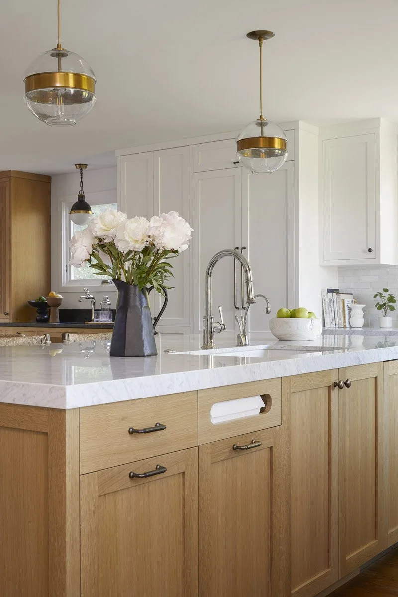 white oak kitchen cabinetry with marble countertop and a vase of peonies