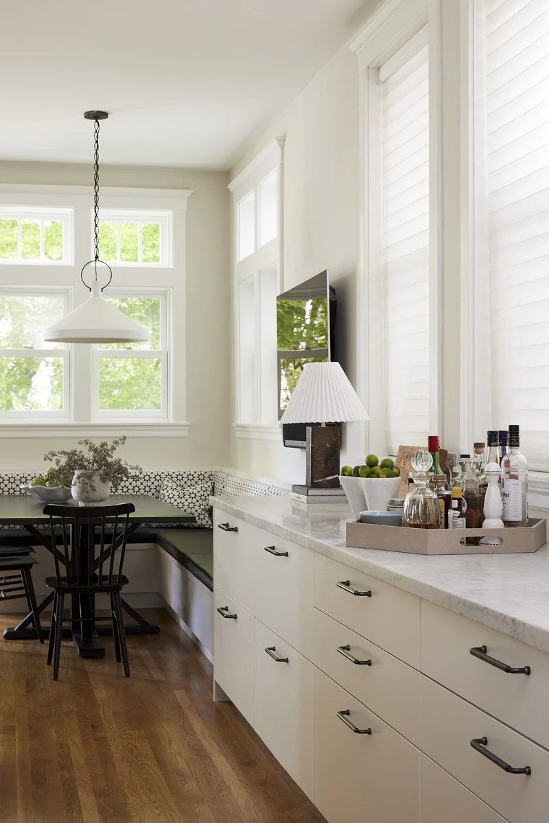 galley kitchen with white cabinetry leading into a breakfast nook