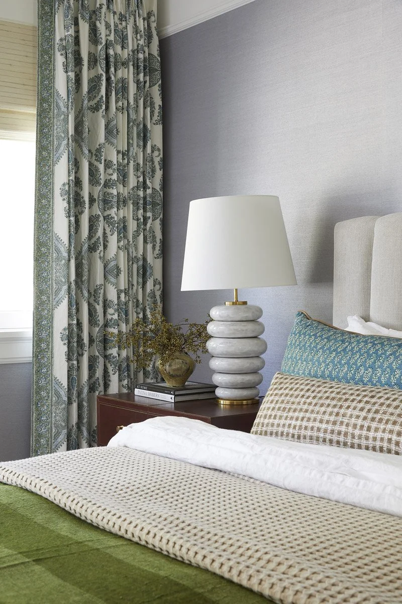 bedside detail with ribbed ceramic lamp and botanical print curtains