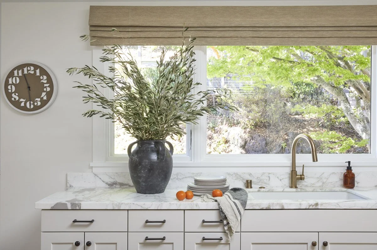 kitchen sink beneath a large window with woven roman shade