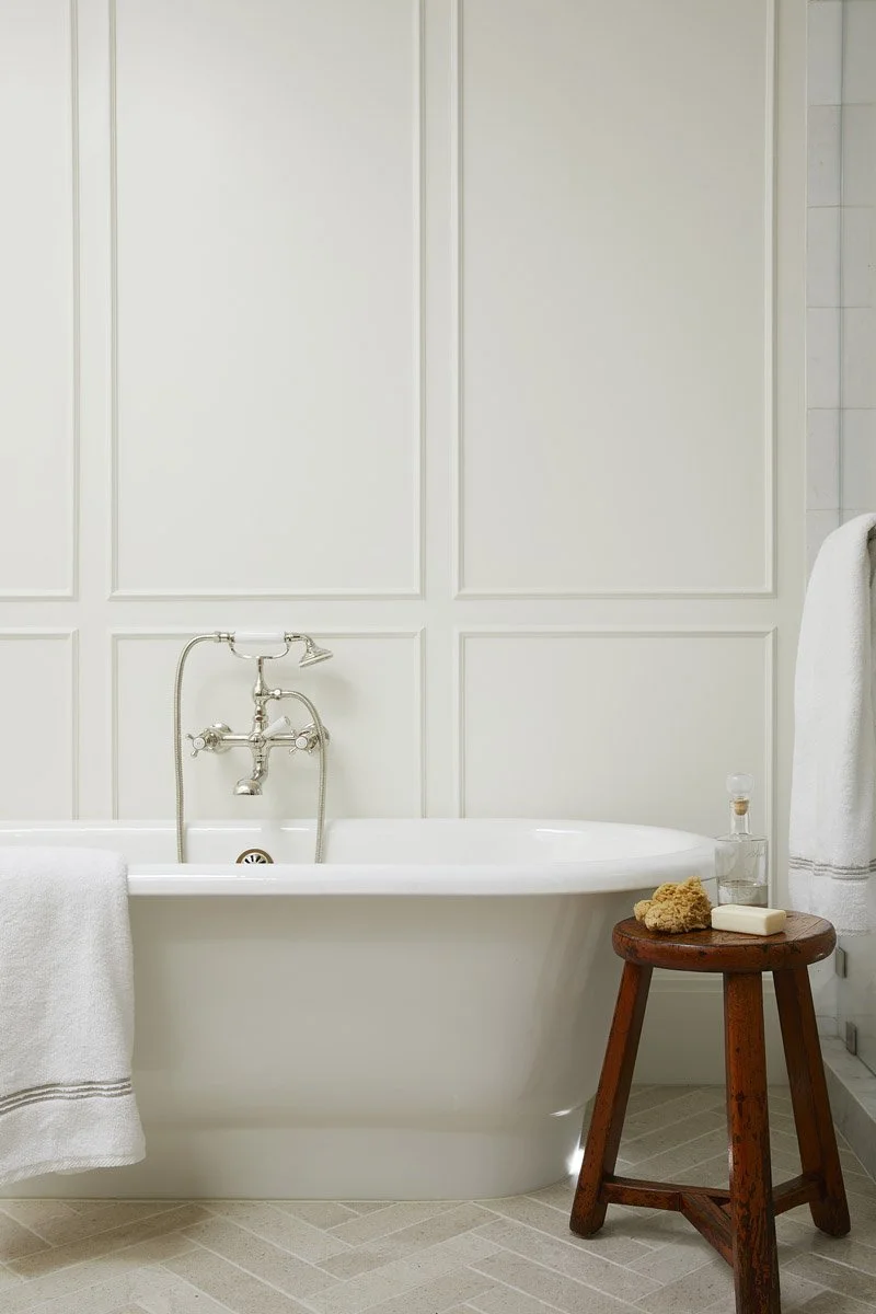 freestanding soaking tub with floor-mounted tap and wooden stool