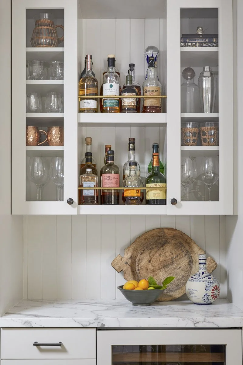 built-in bar cabinet with glass doors, stocked bar and marble countertop