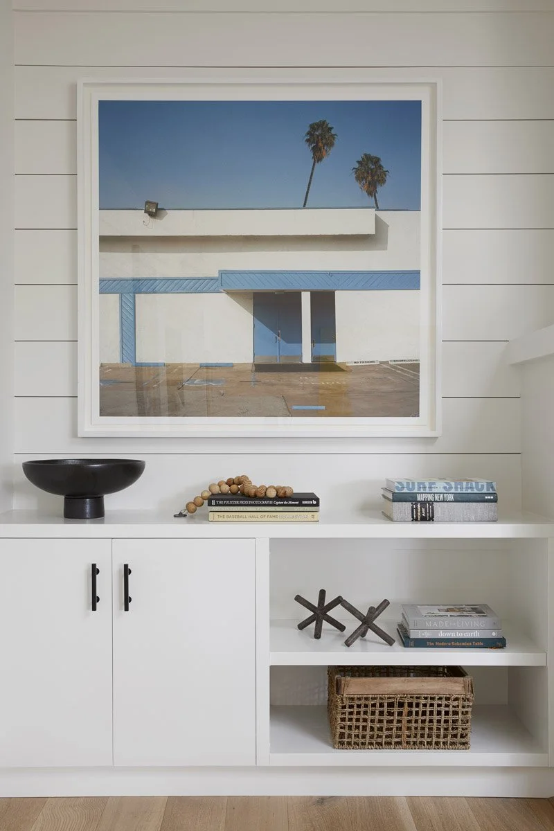 white built-in cabinet with open shelving beneath a framed photograph