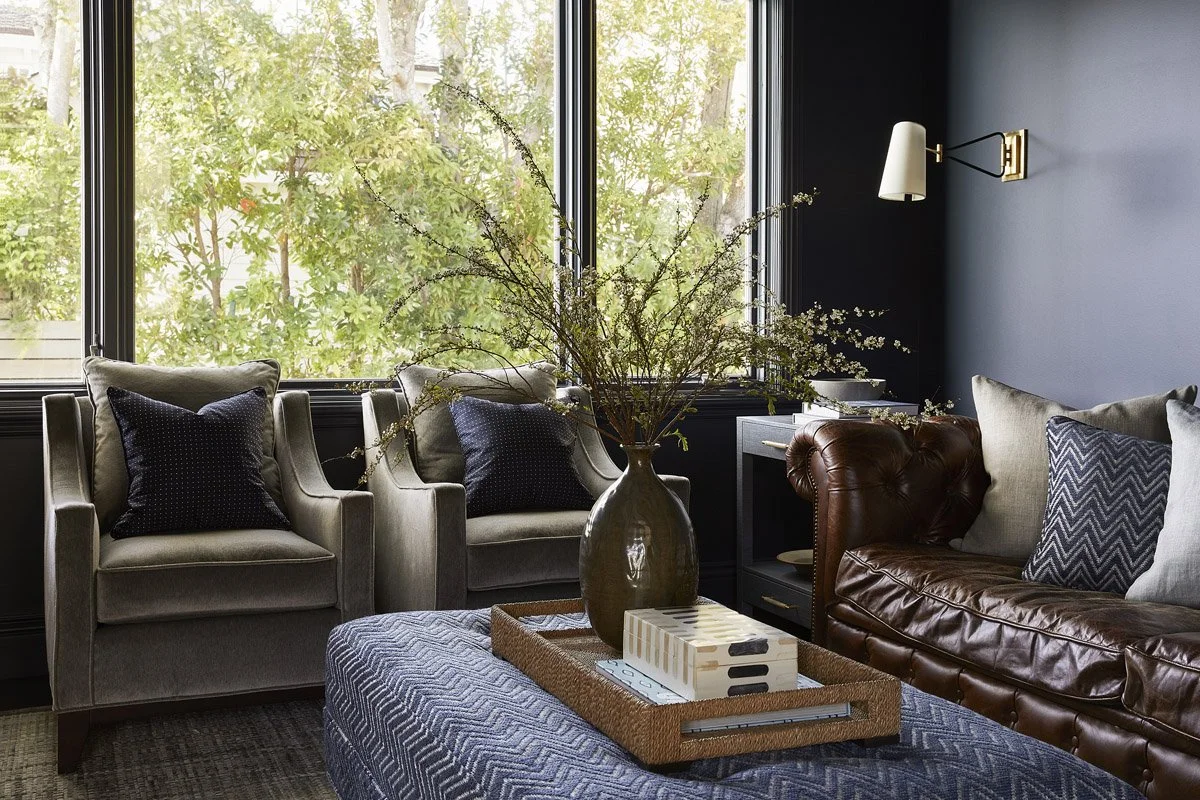 den seating area with velvet armchairs and a tufted leather sofa