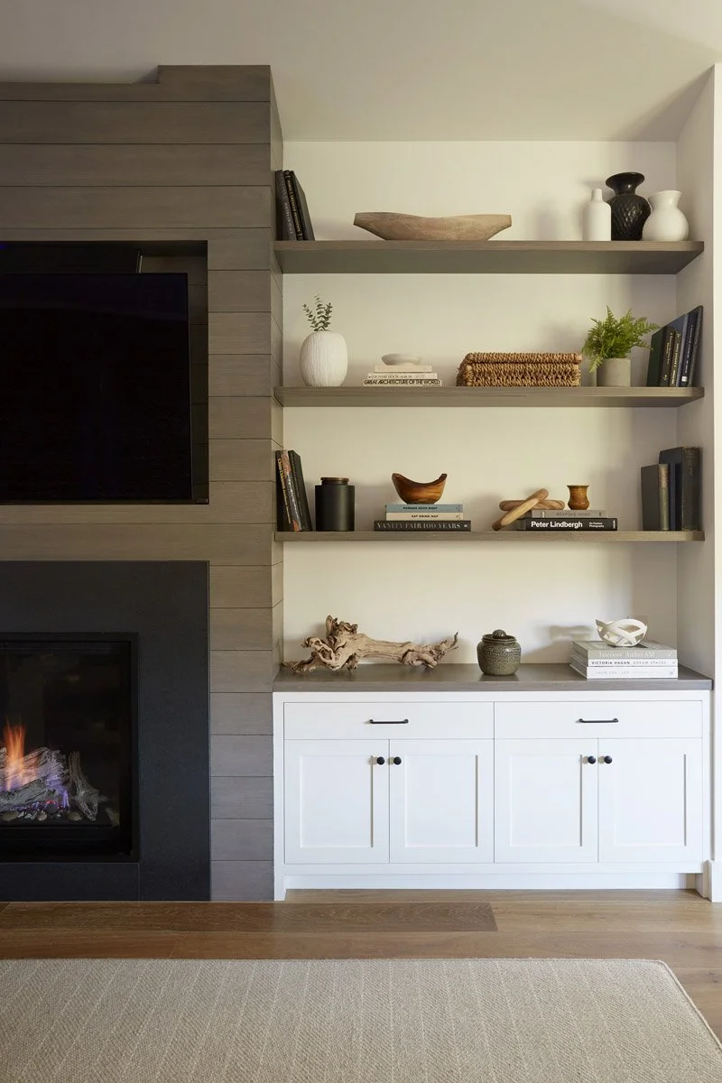 fireplace with floating wood shelves and white lower cabinets