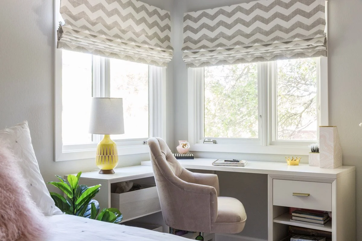 home office with built-in desk, upholstered chair and chevron roman shades