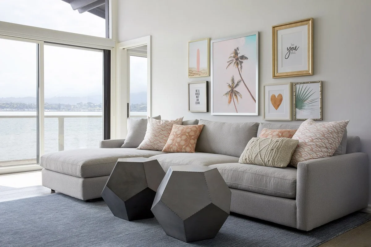 family room with grey sectional, geometric side tables and gallery wall