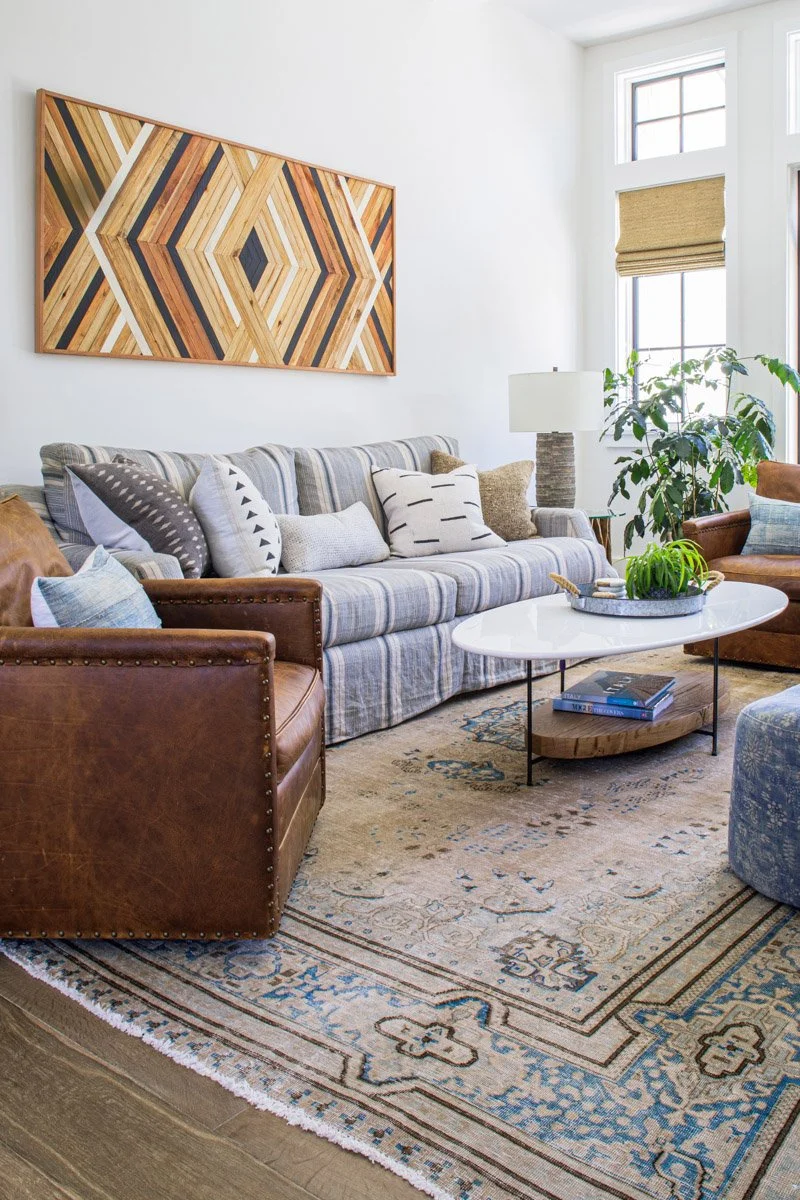 living room with leather sofa, chevron wood wall art and vintage rug