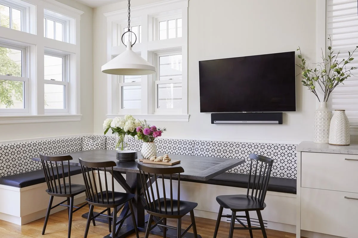 breakfast nook with patterned banquette, black Windsor chairs and wall-mounted TV