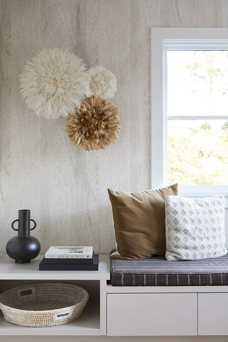 window bench with textured pillows and juju hats on the wall