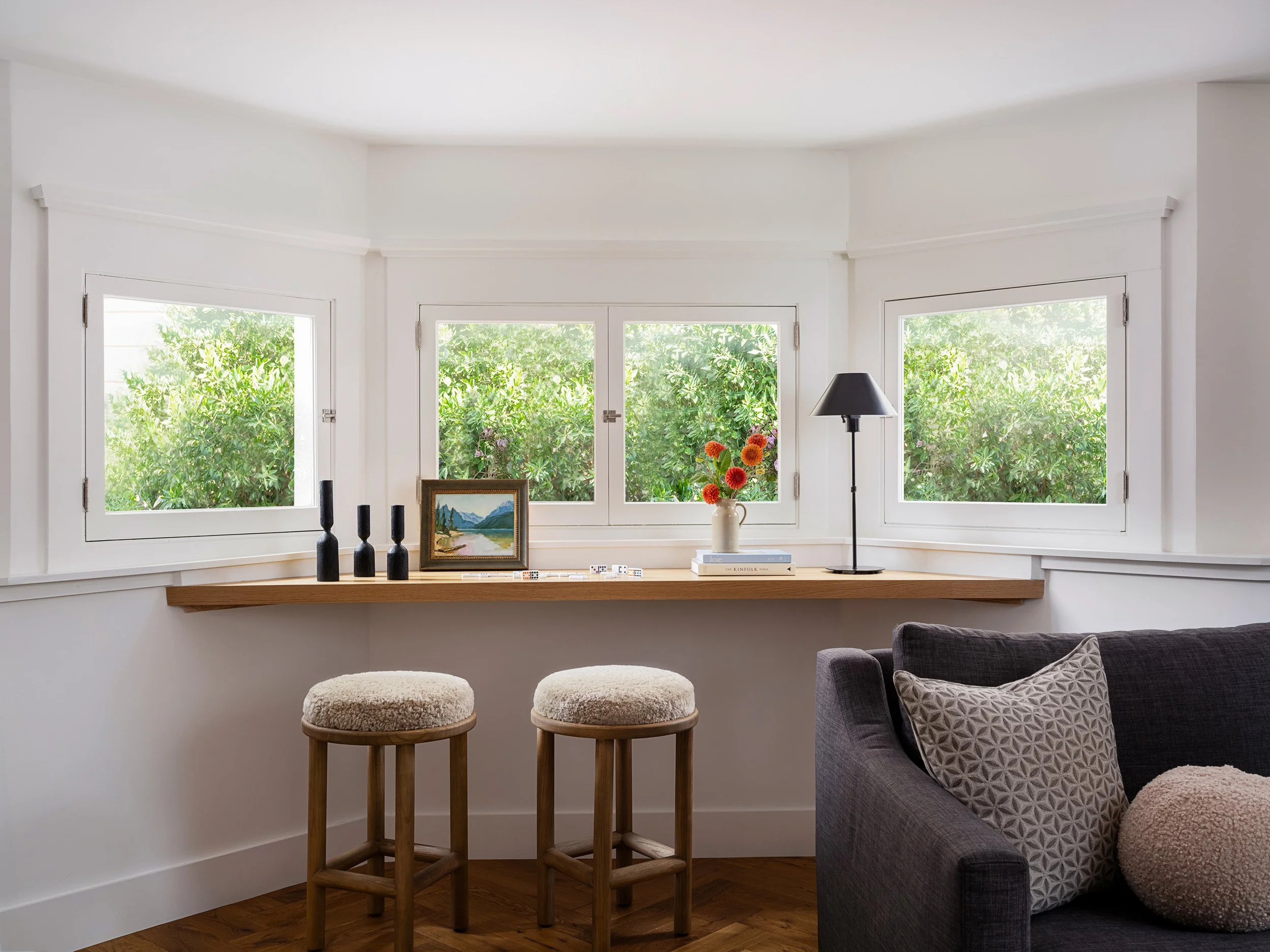 bay window desk with upholstered stools and garden views