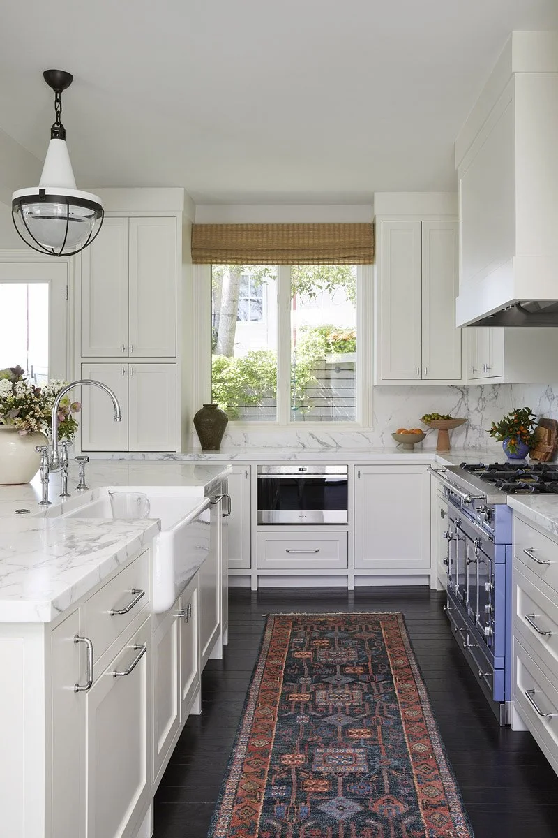 galley kitchen with white cabinetry, farmhouse sink and patterned runner
