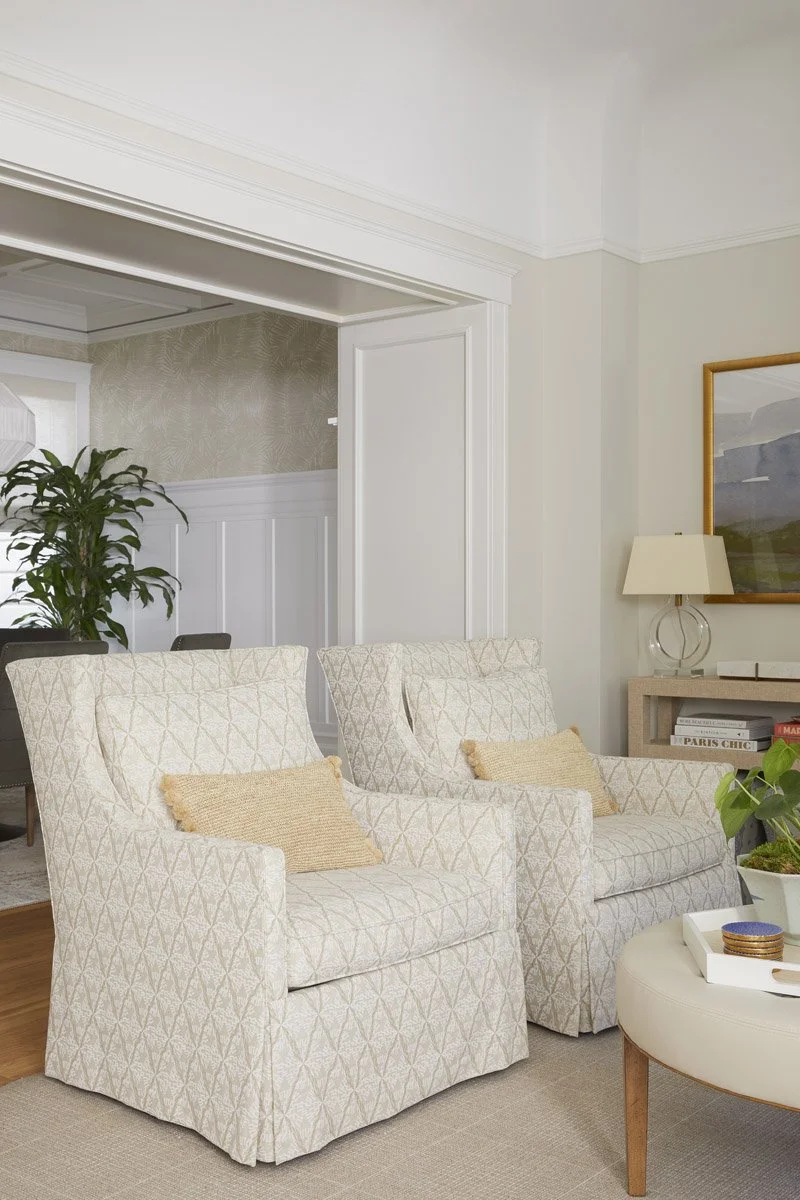 pair of slipcovered armchairs with a round ottoman