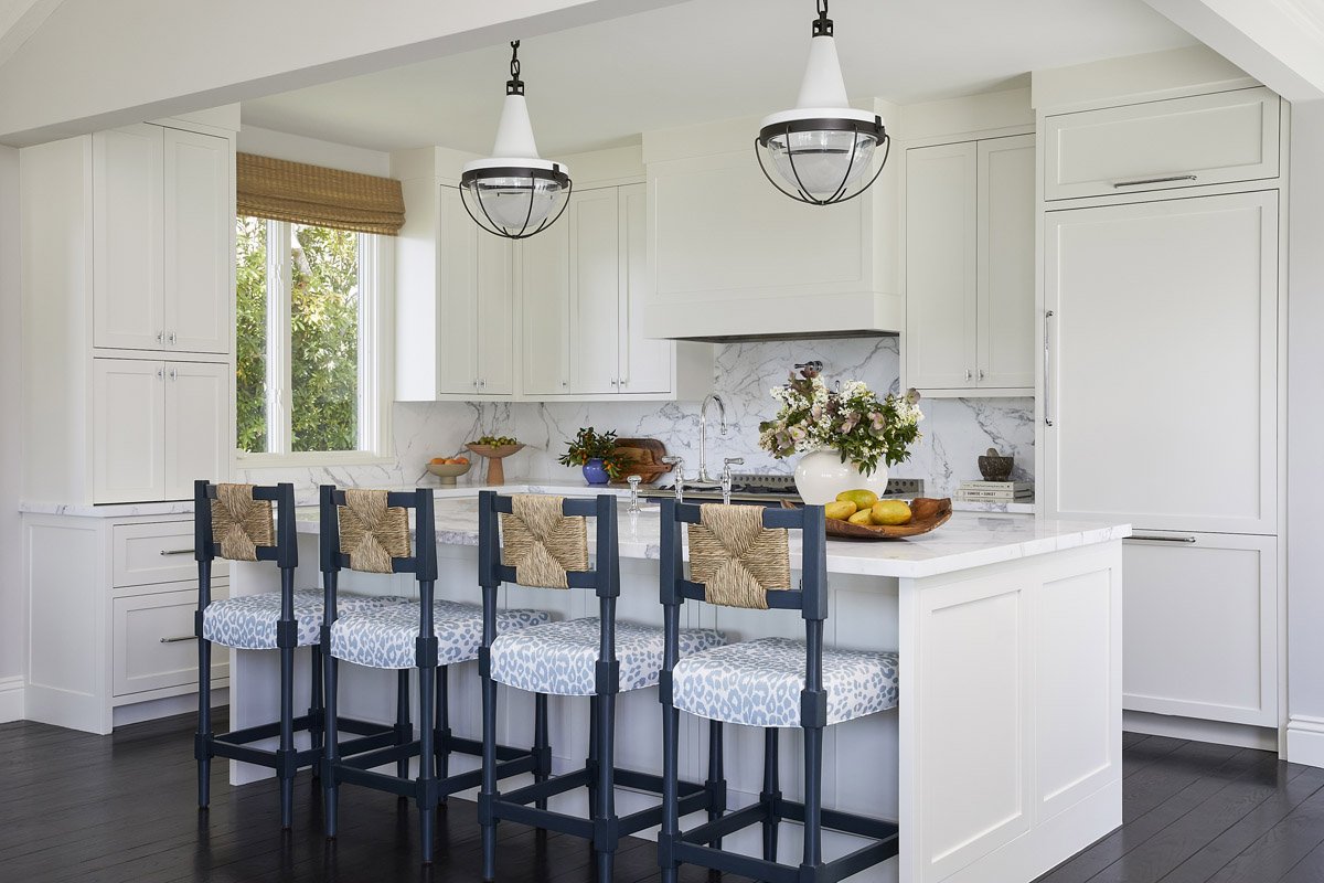 white kitchen with blue counter stools and two glass pendant lights