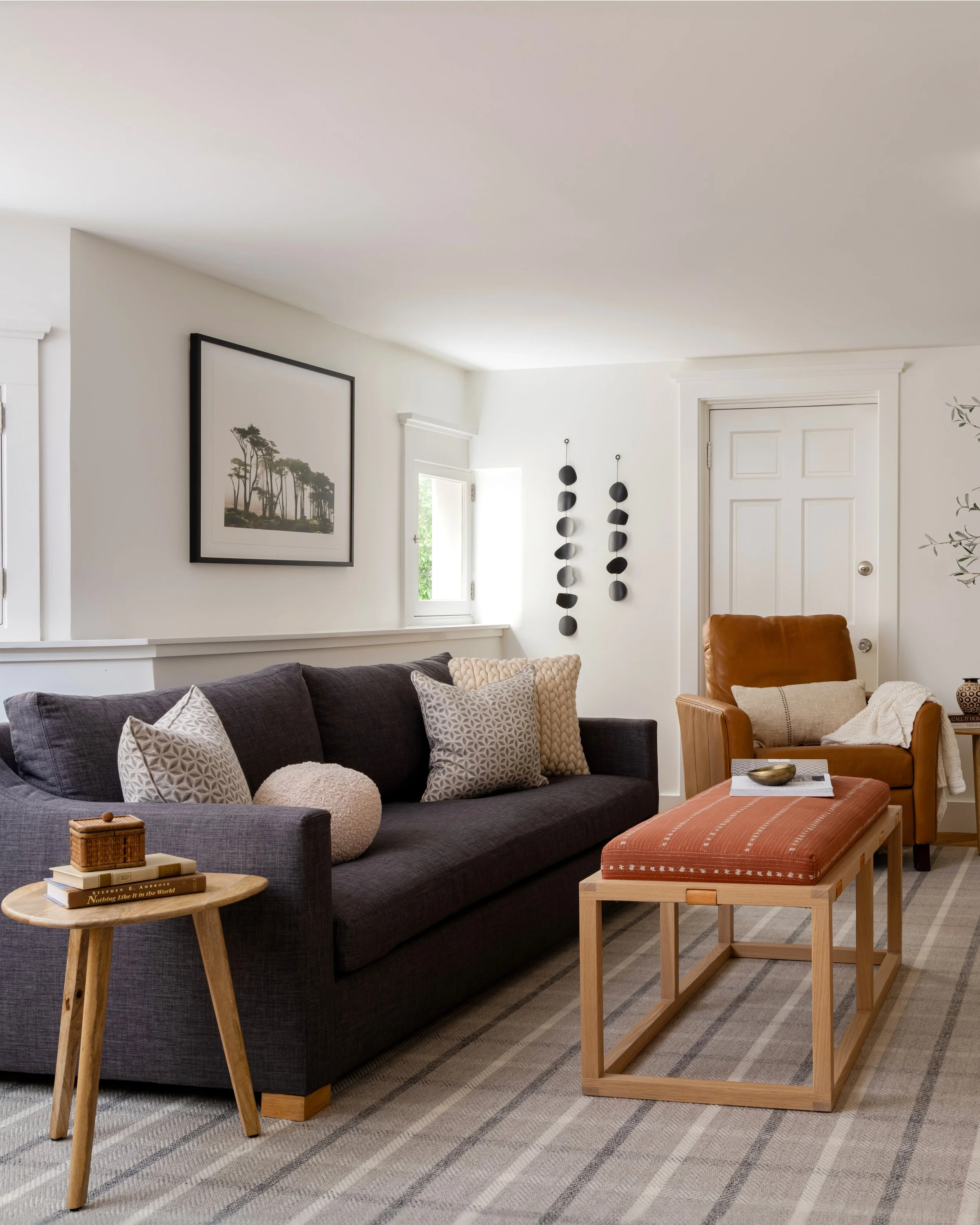 family room with charcoal sofa, wooden side table and framed art