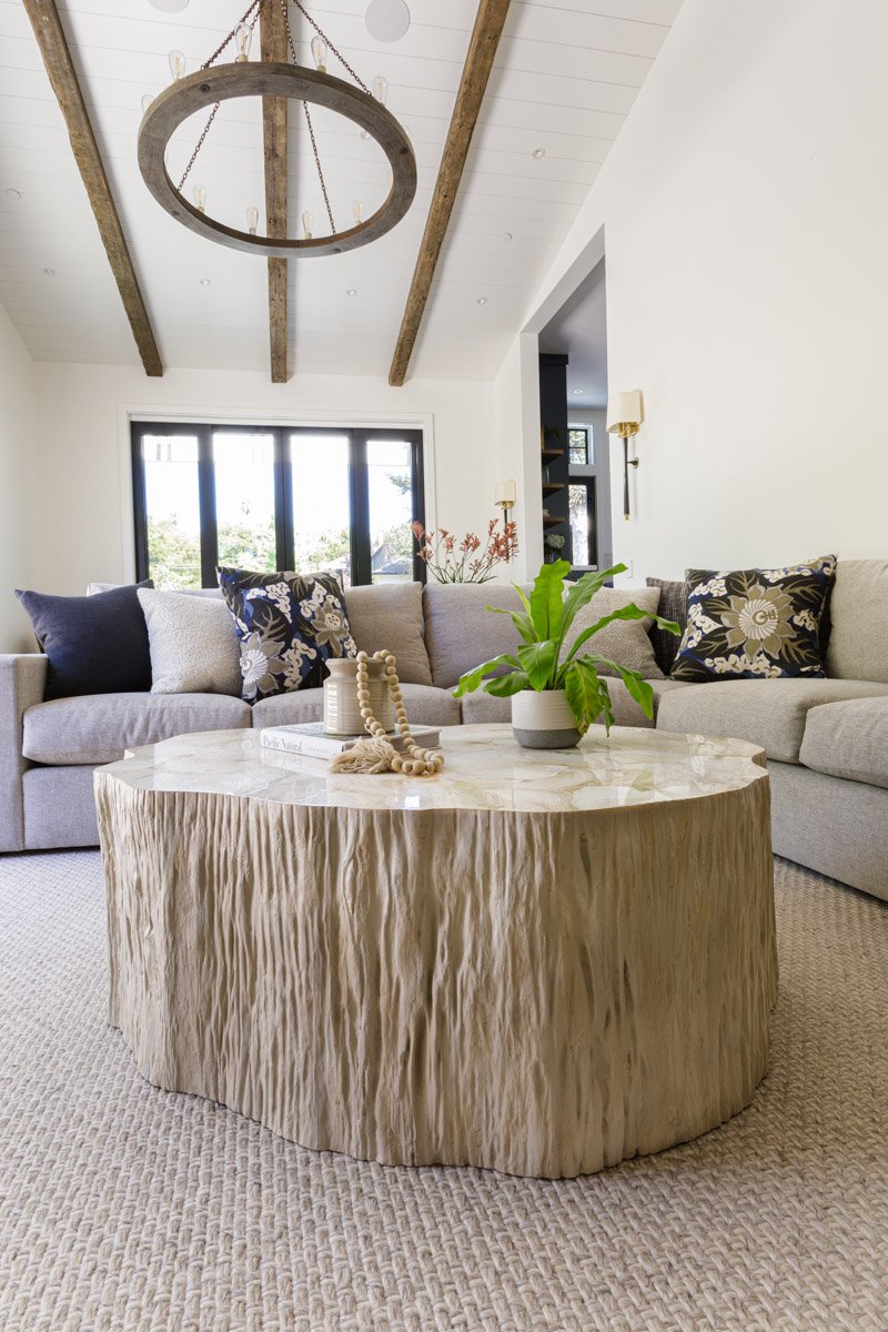 living room with sculptural wood coffee table, white sofa and wood beam ceiling