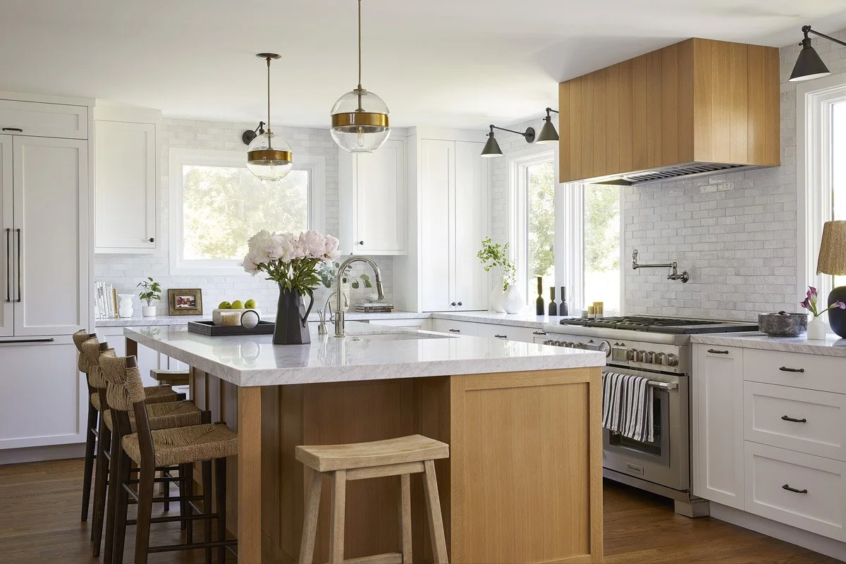 bright kitchen with white oak island, range hood and brass pendants