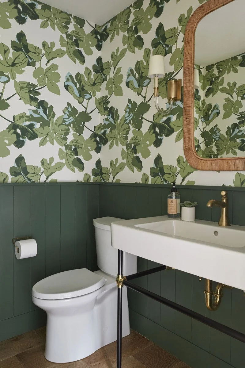 powder room with leaf print wallpaper, green panelling and brass fixtures