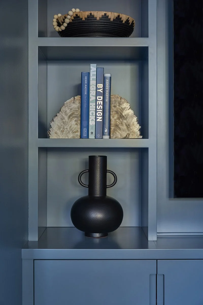 blue built-in shelving styled with books and a black ceramic vase