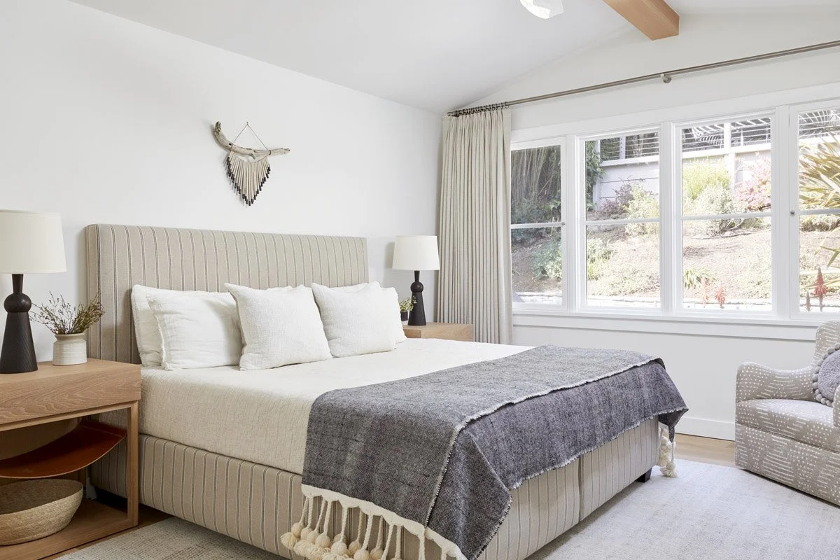 bedroom with upholstered headboard, grey throw and wall-mounted antler decor
