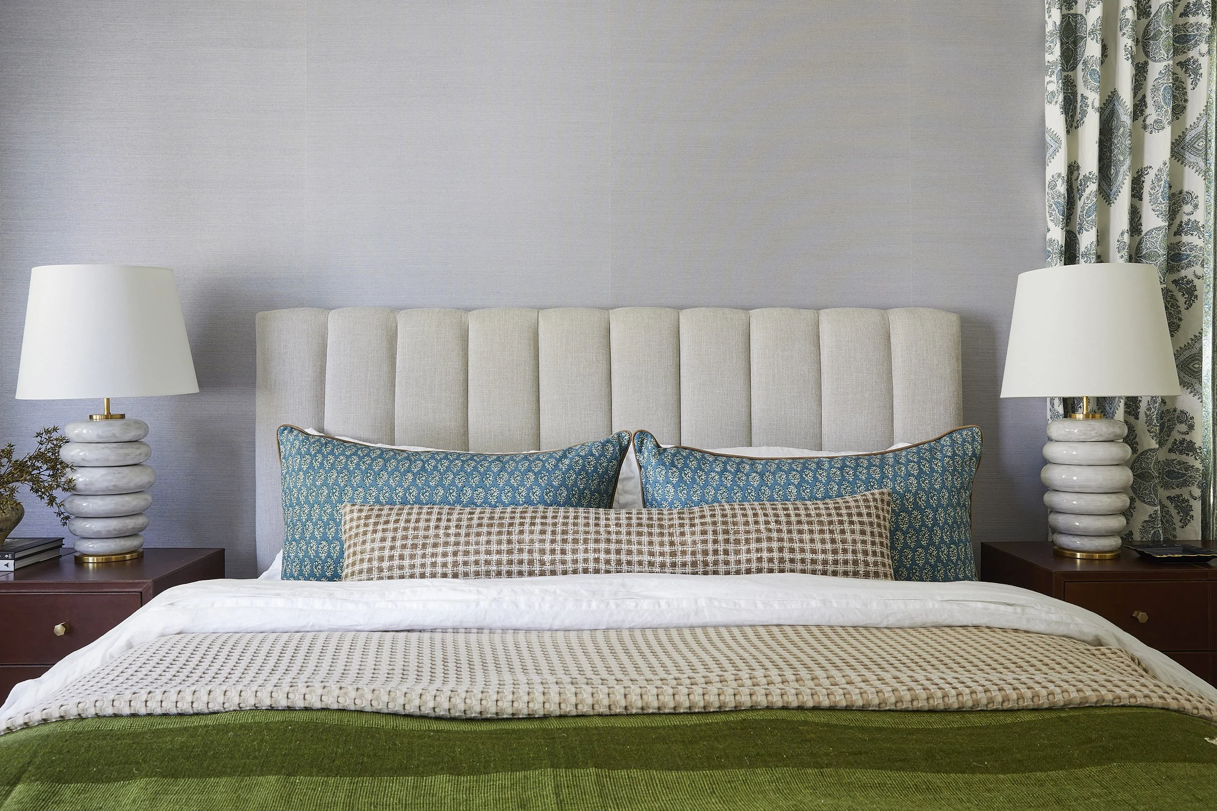 bedroom with channelled headboard, teal pillows and green throw
