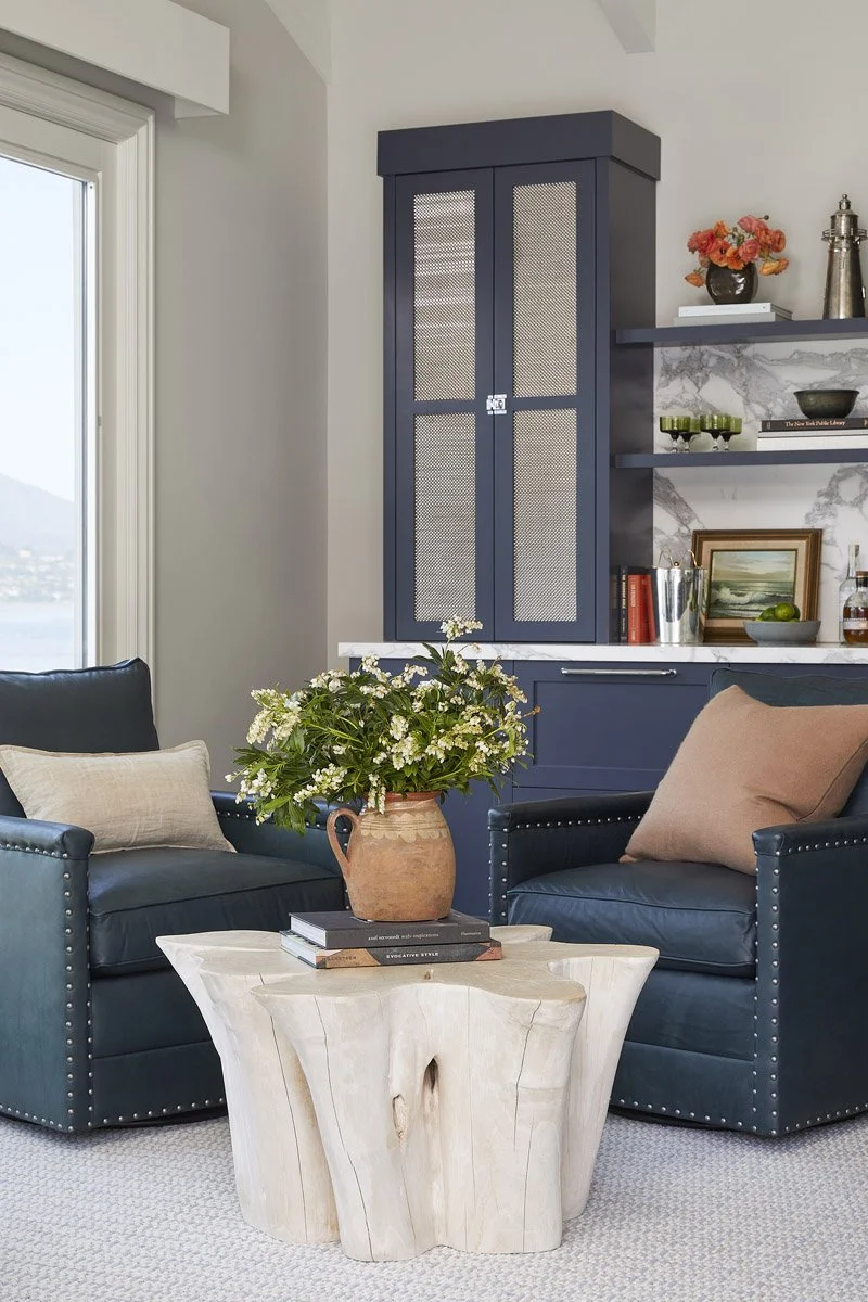 navy leather armchairs around a wooden side table with built-in cabinets behind