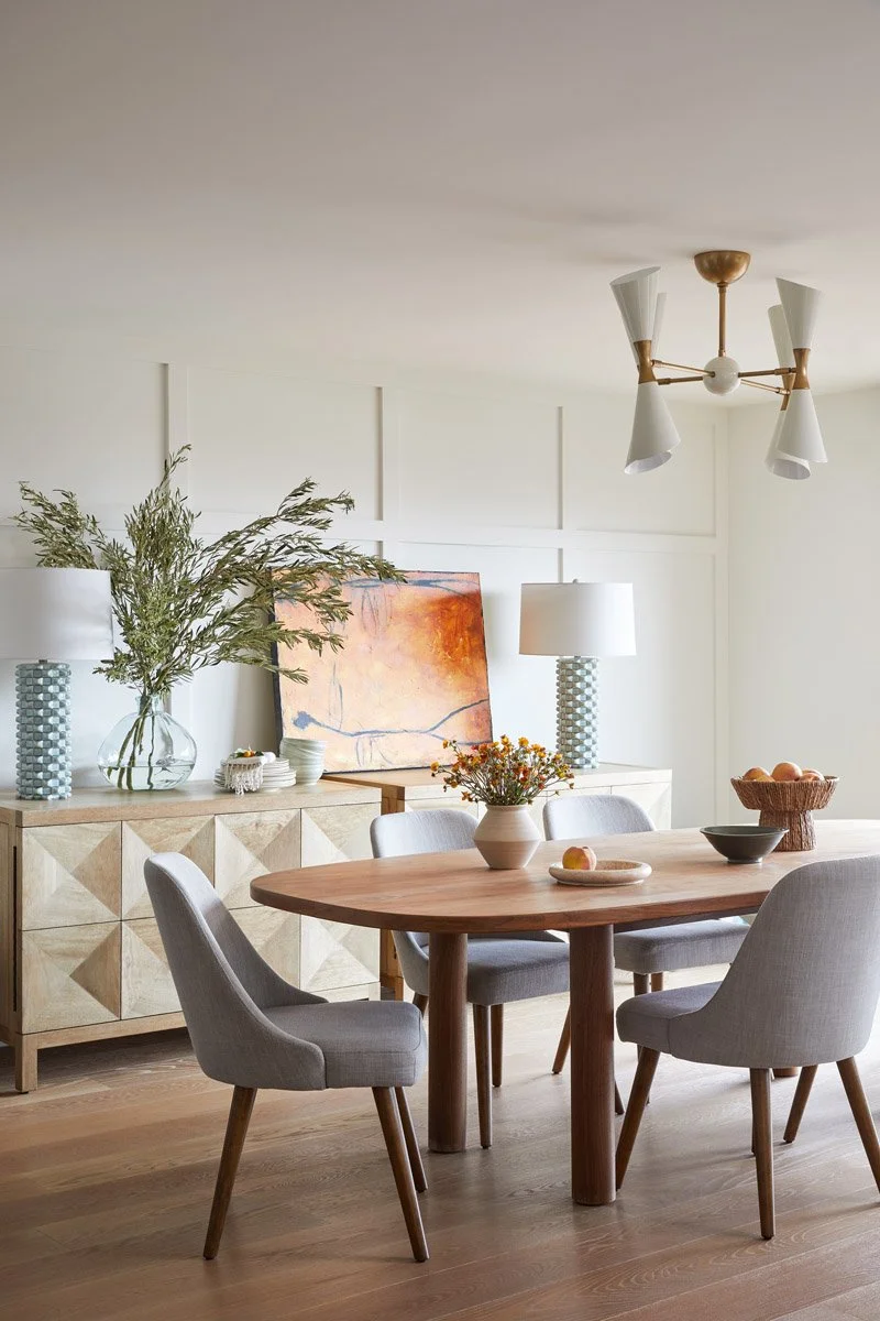 round dining table with grey chairs beneath a brass sputnik chandelier