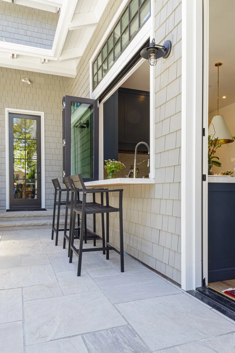 outdoor bar with counter stools under a pass-through kitchen window
