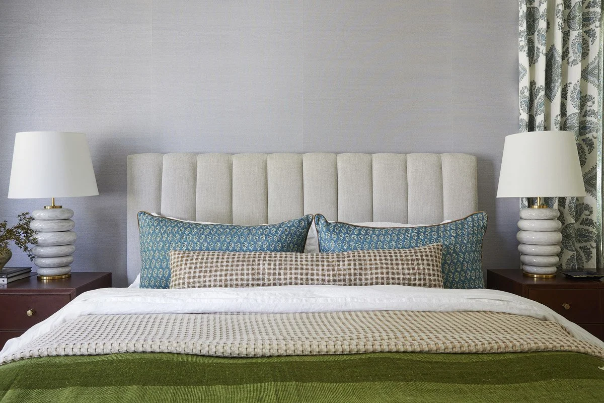 primary bedroom with lavender walls, teal pillows and ceramic bedside lamps
