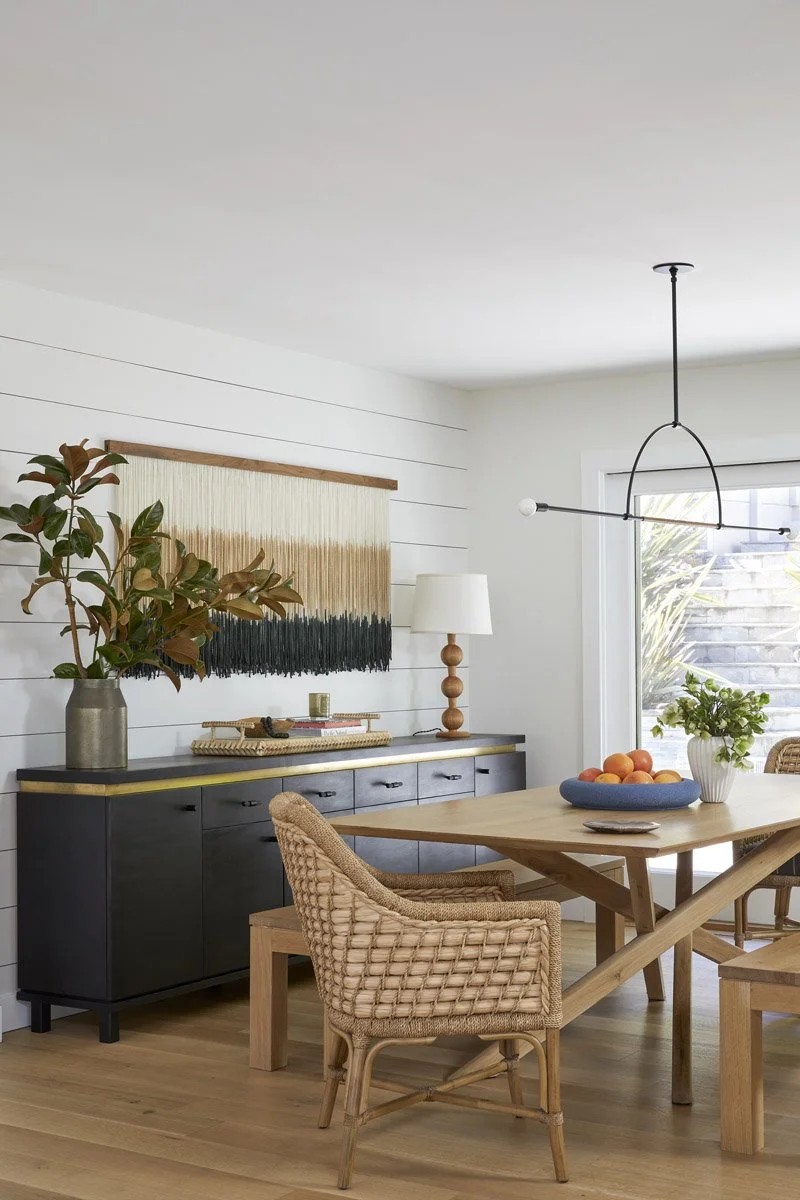 dining room with woven chairs, black sideboard and woven wall hanging