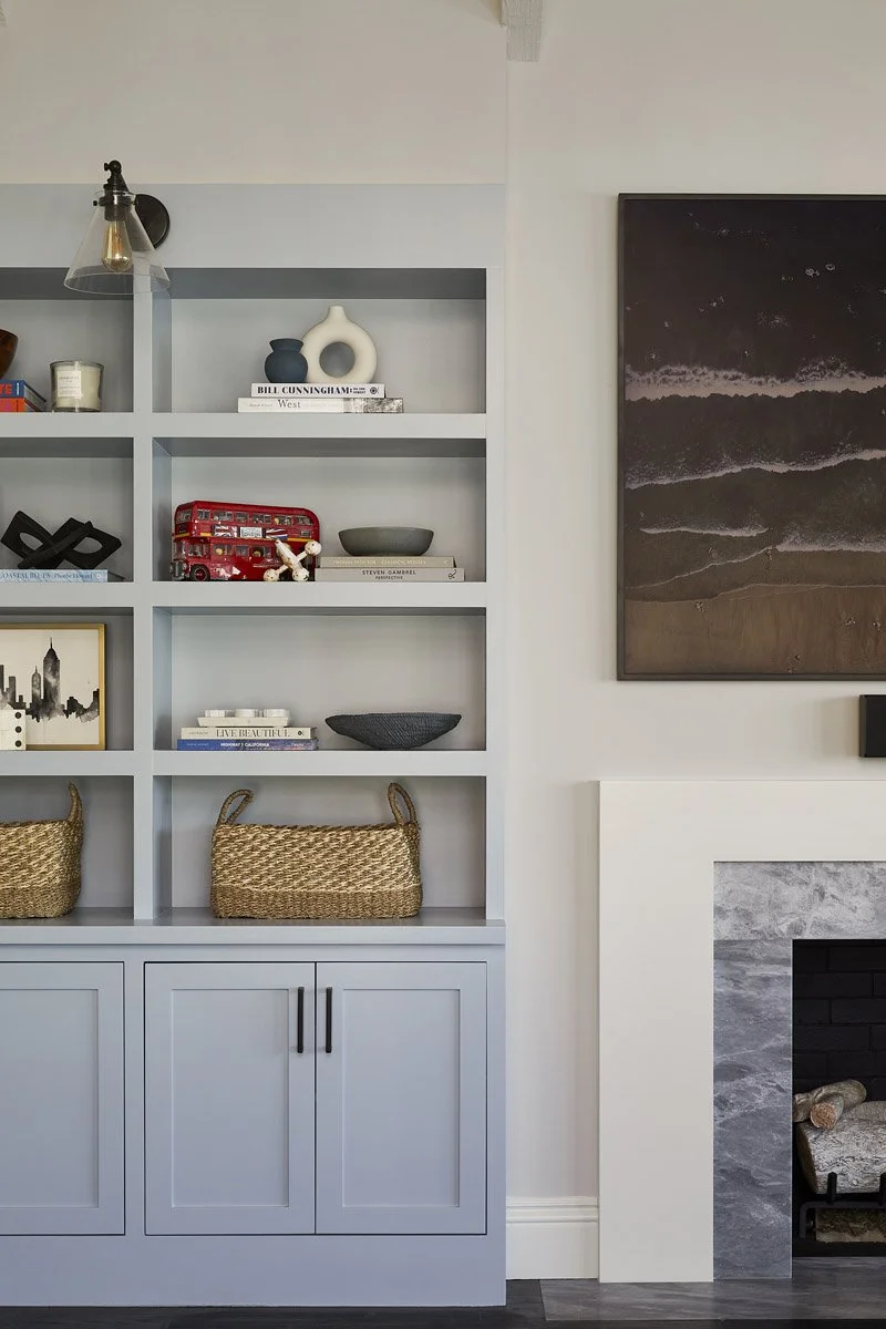 built-in shelving with styled objects beside a marble fireplace