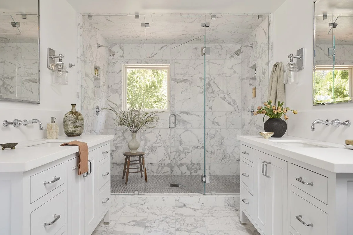 marble bathroom with double vanities and glass walk-in shower